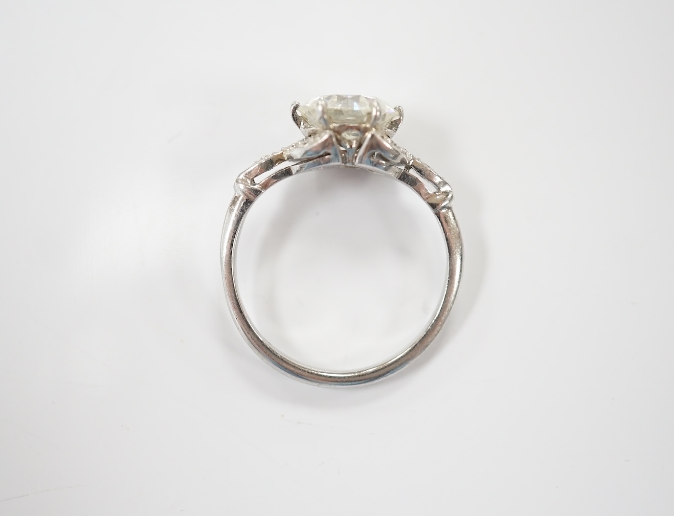 A platinum and single stone diamond set ring, with six stone diamond chip set foliate shoulders, the centre stone weighing 1.60ct, size H/I, gross weight 3.1 grams. Condition - fair